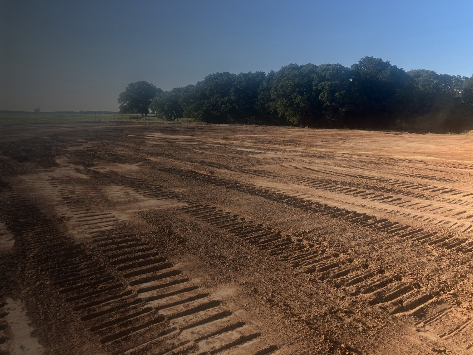 Tractor grading freshly prepared land near a shop building